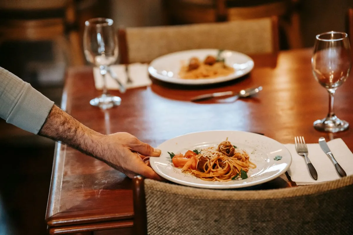 Atendente levando um prato à mesa
